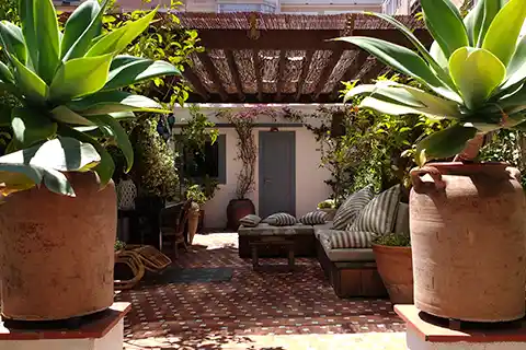 Terraza con pérgola, zona chill-out y grandes macetas con agaves