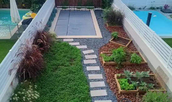 Jardín terminado con césped, camino de losas y bancales de huerto en el Maresme