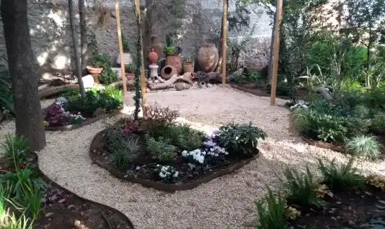 Jardín de sombra con camino de grava y parterres recién plantados