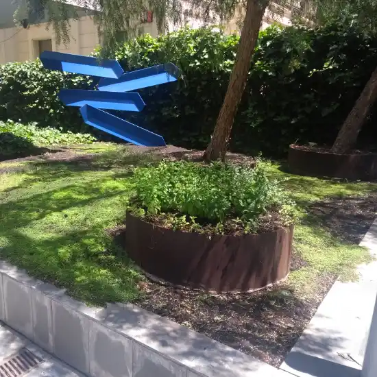 Parterre circular con plantas y escultura azul en un jardín de Barcelona