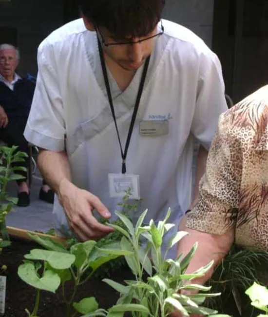 Terapeuta y residentes plantando aromáticas en el huerto de la residencia
